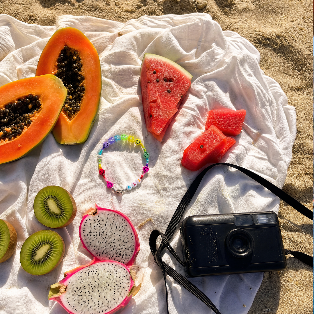 Personalisiertes Armband von from the Valley mit bunten Buchstabenperlen und Süßwasserperle auf sommerlichen Früchten am Strand