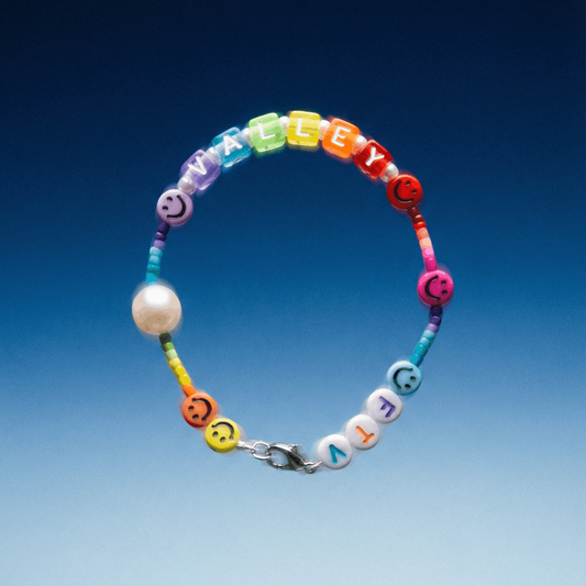Personalisiertes Armband mit bunten Buchstaben-Perlen vor blauem Farbverlauf